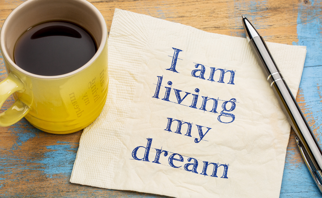 Coffee mug, not " I am living my dream" with a pen off to the side 