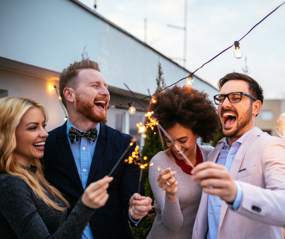 Image of friends laughing and having a good time. They are dressed up and holding sparklers. They know how to look and feel younger. 