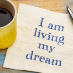 Coffee mug, not " I am living my dream" with a pen off to the side